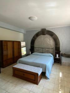 een slaapkamer met een groot bed en een stenen muur bij La casa nel bosco in Trecastagni