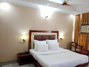 a bedroom with a large bed with white sheets and pillows at HOTEL CORPORATE INN in Chandīgarh
