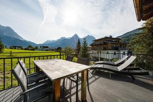 uma mesa de madeira e cadeiras numa varanda com montanhas em Bergheimat Tirol em Lermoos