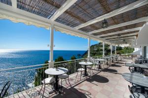 a patio with tables and chairs and the ocean at Maresca Hotel Praiano in Praiano