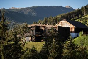 a barn on a hill with mountains in the background at naturApart in Brunico