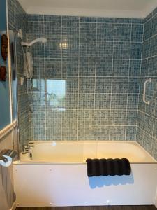 Un baño con bañera y pared de azulejos. en Holly Cottage, en Glencoe
