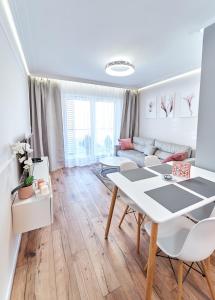 a white living room with a table and a couch at LAGUNA Apartament Polanica Residence 28 in Polanica-Zdrój