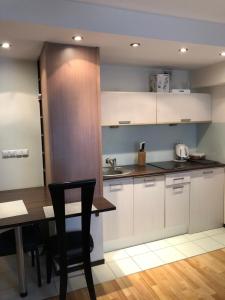a kitchen with white cabinets and a table and a sink at Apartament 117 in Krynica Zdrój