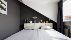 a bedroom with a large bed with a black wall at HuisjehurenEgmond in Egmond aan Zee