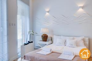 a white bedroom with a large bed with two towels on it at Apartamenty Marea - visitopl in Międzyzdroje