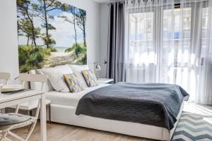 een slaapkamer met een bed, een bureau en een raam bij Apartamenty Na Zdrojowej - visitopl in Świnoujście