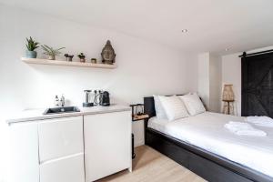 ein kleines Schlafzimmer mit einem weißen Bett und einem Waschbecken in der Unterkunft Little Buddha in Zandvoort