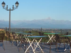 eine Reihe von Tischen und Stühlen auf einem Balkon mit Bergblick in der Unterkunft Enolocanda Del Tufo in Dogliani