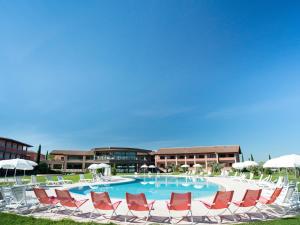 a large swimming pool with lounge chairs and umbrellas at Valle di Assisi Hotel & Spa in Assisi
