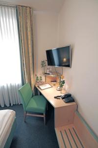 a room with a desk, chair and a television at Hotel am Hofgarten in Düsseldorf