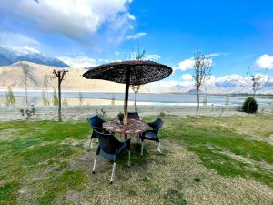 a table and chairs with an umbrella in the grass at Indus View Hotel Skardu in Skardu