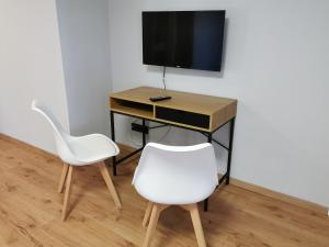 escritorio con 2 sillas blancas y TV en Gästehaus Vergissmeinnicht en Guteborn