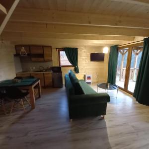 ein Wohnzimmer mit einem grünen Sofa und einem Tisch in der Unterkunft ZACISZE ,,Jastrząb'' domek na Kaszubach z balią z jacuzzi in Brodnica Dolna