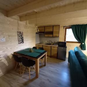 eine Küche und ein Wohnzimmer mit einem Tisch und einem Sofa in der Unterkunft ZACISZE ,,Jastrząb'' domek na Kaszubach z balią z jacuzzi in Brodnica Dolna
