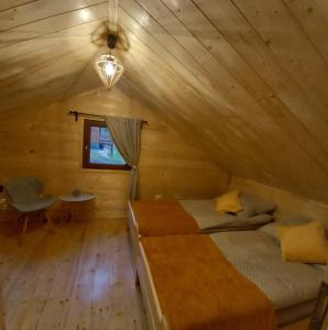 ein Schlafzimmer in einem Blockhaus mit einem Bett und einem Fenster in der Unterkunft ZACISZE ,,Jastrząb'' domek na Kaszubach z balią z jacuzzi in Brodnica Dolna