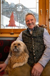 Un hombre con chaleco sentado al lado de un perro en Gasthaus-Pension Golfvilla en Pertisau