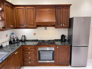 a kitchen with wooden cabinets and a stainless steel refrigerator at Sunrise Apt near beach SmartTV & Netflix in Birżebbuġa