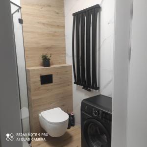 a bathroom with a toilet and a washer and dryer at Apartament Pomerania 2 in Kołobrzeg