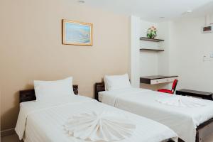 duas camas com lençóis brancos num quarto em Corner One Residence em Hat Yai