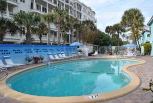 a large swimming pool with chairs and a building at Sand Dune Shores, a VRI resort in Palm Beach Shores