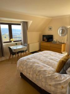 a bedroom with a bed and a desk and a table with a chair at Tor View in Portree