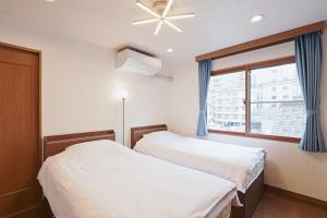 twee bedden in een kamer met een raam bij Mon Petit Chat in Kanazawa