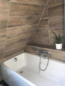 a white bath tub in a bathroom with a tile wall at Chambre d'Hotes Les Hortensias in Rang-du-Fliers