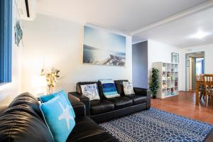 un soggiorno con divano in pelle nera e cuscini blu di Relax in San Remo a San Remo