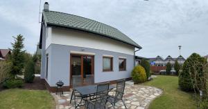 Casa blanca pequeña con mesa y sillas en MB House Sarbinowo en Sarbinowo