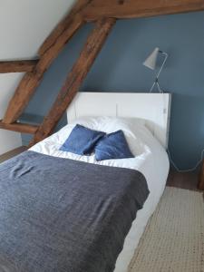 Una cama con dos almohadas azules encima. en les gîtes Gillois en Gilles