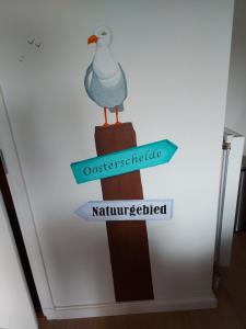 a directional sign with a duck on a wooden pole at De Nieuwe Stal in Scherpenisse