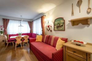 een woonkamer met een rode bank en een tafel bij Residence As'Odei in San Cassiano