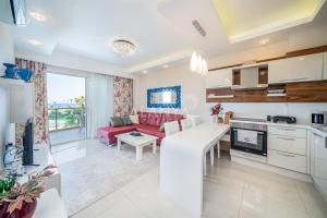 een witte keuken en een woonkamer met een rode bank bij Calista Premium Residence in Alanya