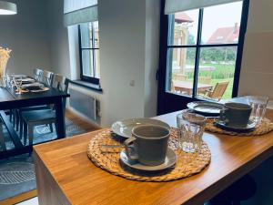 a table with two cups and plates on top of it at Karkle SummerHOUSE, sea view villa in Karklė