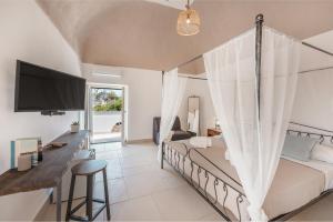 a bedroom with a bed and a desk and a tv at Cala Cala Rooms,Restaurant & Farm Experience in Procida