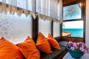 un asiento junto a la ventana con almohadas naranjas y un jarrón de flores en Beach House Apartment en Side