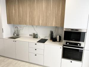 a white kitchen with a sink and a microwave at Caсtus Apartments 1 in Ivano-Frankivsk +8 photos