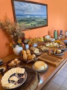 einen Tisch mit viel Brot und Teller mit Speisen in der Unterkunft Pousada Rosa dos Ventos in Delfinópolis