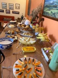 una larga mesa de madera con platos de comida. en Pousada Rosa dos Ventos, en Delfinópolis