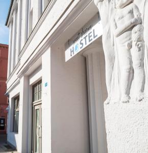 um sinal na lateral de um edifício com uma estátua em sweet dream hostel & pension - Self Check-In em Güstrow