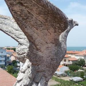 una grande statua di pietra di uccello seduta sopra un edificio di HOTEL ROSSINI a Rimini