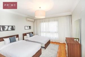 a bedroom with two beds and a table at Prime Select Arkadia Nile View in Cairo