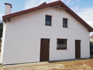 uma casa branca com um telhado castanho em Domek przy stajni em Gajrowskie