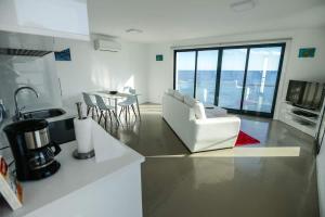 cocina y sala de estar con muebles blancos y ventana grande en CASA DAS TAIPAS, en Vila Franca do Campo