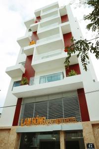 a tall white building with a sign in front of it at Lam Hồng Apartment & Hotel in Nha Trang