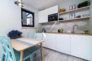 a kitchen with white cabinets and a wooden table and chairs at Letnisko in Władysławowo