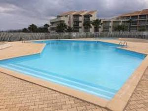 einem großen Pool mit blauem Wasser vor einem Gebäude in der Unterkunft LES GOELLETTES : vue mer et piscine in Saint-Cyprien