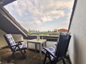 einen Balkon mit einem Tisch, 2 Stühlen und einem Fenster in der Unterkunft Nordseeblick in Horumersiel