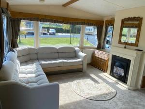 a living room with a couch and a fireplace at Happydays Caravan hire Whithorn 1 in Bailliewhir